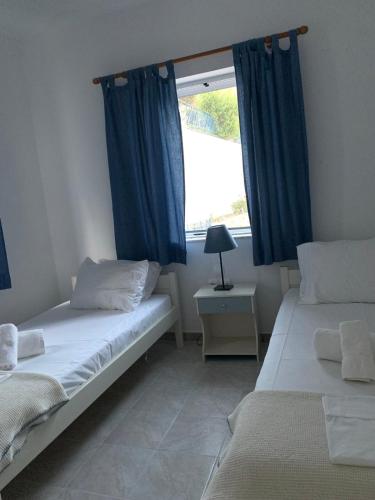 a bedroom with two beds with blue curtains and a window at Aegean Aura Apartment II in Kalymnos