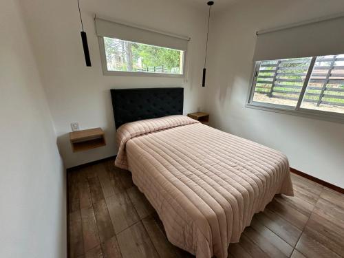 1 dormitorio con 1 cama y 2 ventanas en La Lomada Villa Gesell en Villa Gesell