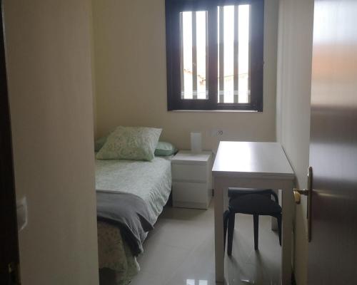 um quarto com uma cama, uma secretária e uma janela em Céntrico apartamento en Corrubedo em Corrubedo