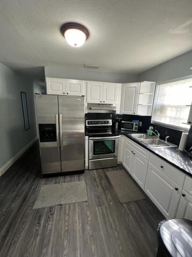 a kitchen with stainless steel appliances and white cabinets at “La Casita” Beautiful home in the heart of Miami ! in Miami