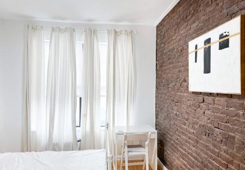 1 dormitorio con pared de ladrillo, cama y mesa en Gorgeous 2 Bedroom apartment in NYC!, en Nueva York