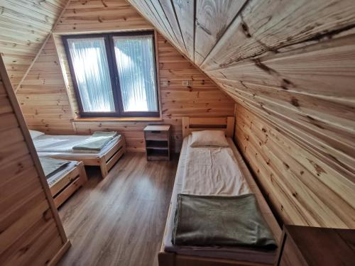 a room with two beds in a wooden cabin at Domki Pod Sosnami in Raków