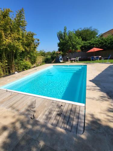 a blue swimming pool with a wooden deck at Maison avec jardin arboré in Saint-Nazaire