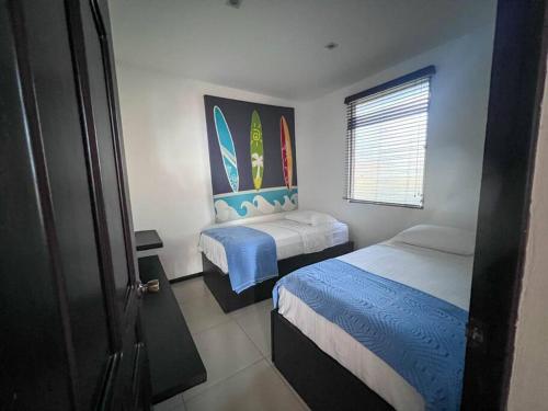 1 dormitorio con 2 camas y tablas de surf en la pared en Casa en el Risco en La Libertad