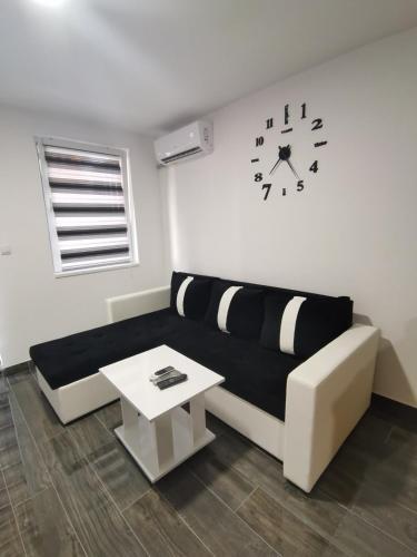 a living room with a couch and a clock on the wall at Apartman Repac in Ostrovo