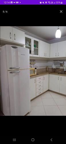 eine Küche mit weißen Schränken und einem weißen Kühlschrank in der Unterkunft Apartamento a 2 Minutos da Praça! in Domingos Martins