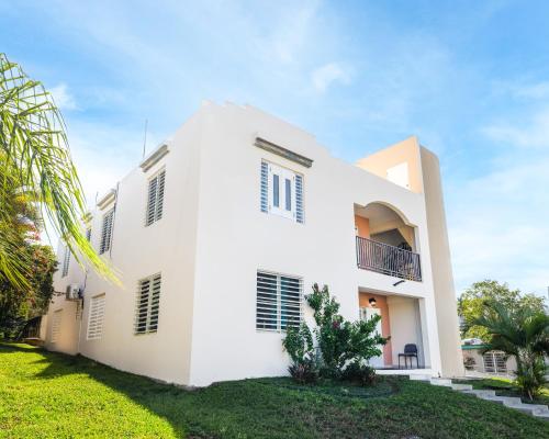 a white house with a green yard at Colinas del Atlantico Vacational House 2nd Floor in Isabela