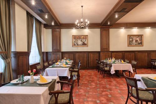 a dining room with tables and chairs and a chandelier at Hotel Traube in Mediaş