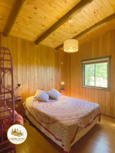 a bedroom with a bed in a wooden room at Cabaña La Paz in San Andrés de Giles