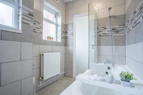 a white bathroom with a tub and a window at STAYZED E - NG7 Free WiFi, Parking, Stylish House Near City Centre - Great For Tourists, Families, Contractors & Long Stays in Nottingham