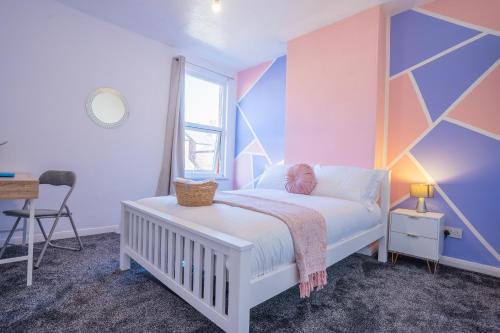 - une chambre avec un lit blanc et un mur géométrique dans l'établissement STAYZED E - NG7 Free WiFi, Parking, Stylish House Near City Centre - Great For Tourists, Families, Contractors & Long Stays, à Nottingham