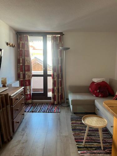un salon avec un canapé et une fenêtre dans l'établissement Appartement les deux alpes+parking couvert, à Les Deux Alpes