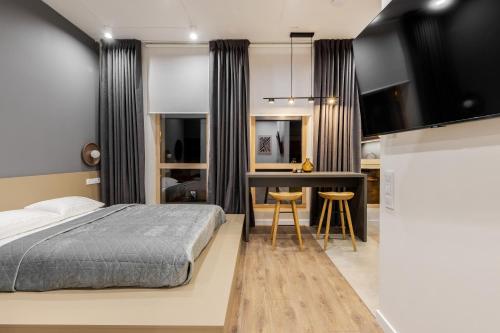 a bedroom with a bed and a desk and a kitchen at FORUM apart in Lviv