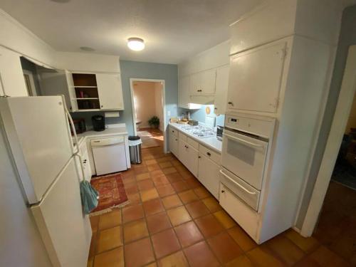 アセンズにあるWhole House in Athens, Private, Fenced, Convenient, Close to Downtownの茶色のタイルフロアのキッチン(白い家電製品付)