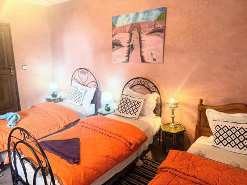 2 camas en una habitación con naranja y blanco en Riad Essaoussan, en Marrakech