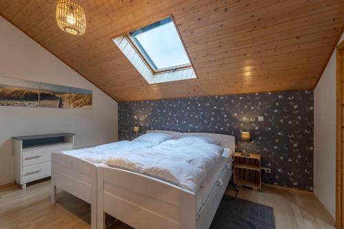 a bedroom with a white bed and a skylight at Ferienwohnung Schädel in Reichshof 