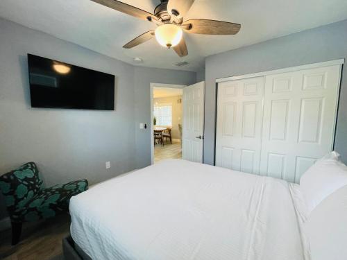 a bedroom with a white bed and a ceiling fan at Sarasota Paradise Heated Pool Home Near IMG & Siesta Key Beach in Sarasota
