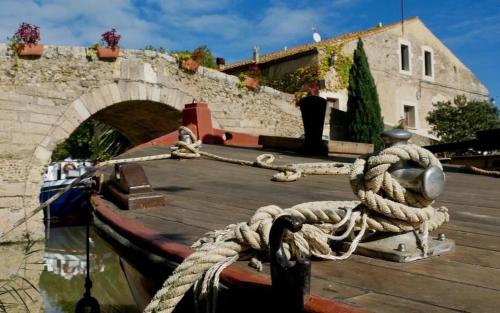 a boat tied to a dock with a rope at Villa Napoléon Piscine&Jacuzzi in Le Somail