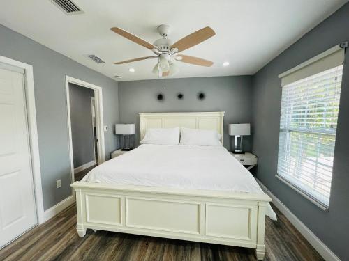 a bedroom with a white bed with a ceiling fan at Sarasota Paradise Heated Pool Home Near IMG & Siesta Key Beach in Sarasota