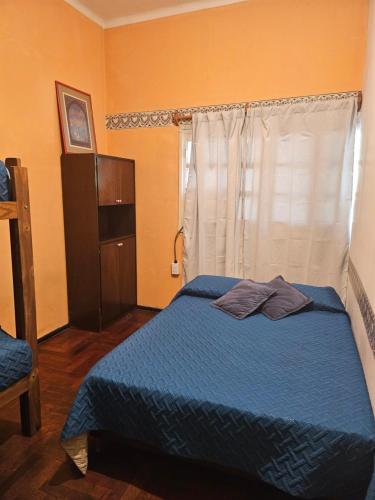 Un dormitorio con una cama azul y una ventana en Hostel Black Lions en Mendoza