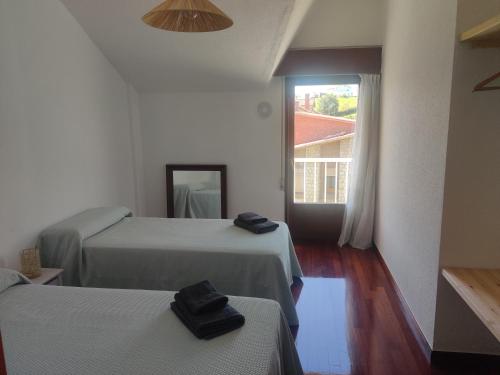 a hotel room with two beds and a window at La Casa de Boo in Boó de Piélagos