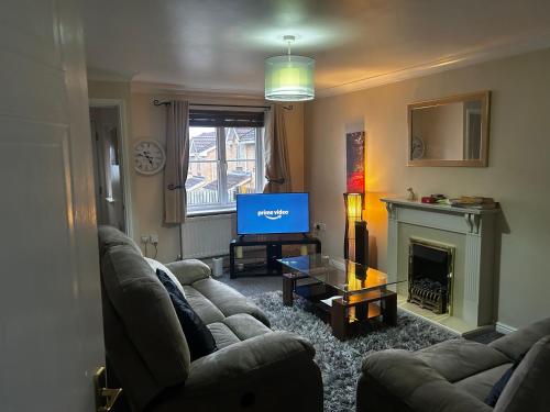 a living room with a couch and a television at Brades Rise House - 3 bedroom house with 2 toilets with a private garden in Birmingham