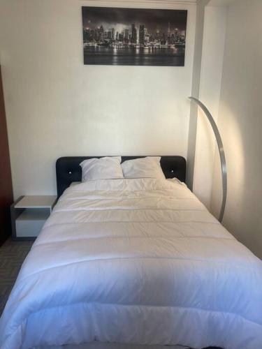 - un lit avec des draps blancs et une photo sur le mur dans l'établissement Appartement Croix rousse 69004, à Lyon