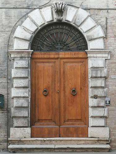 a wooden door on a building with an arch at Palazzo Trevisani in Porto San Giorgio