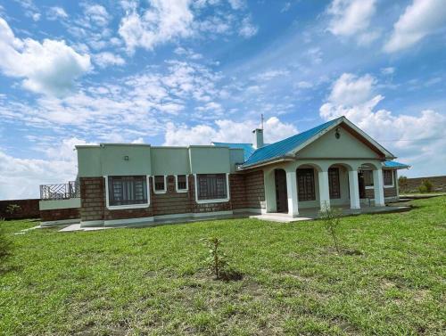 a small house with a blue roof on a field at Riri Country Living Isinya in Kitengela 