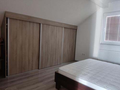 a bedroom with wooden cabinets and a white bed at Selma in Vogošća