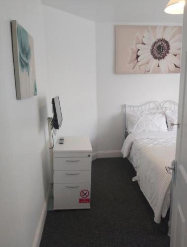 a bedroom with a bed and a white dresser with a flower picture at Fresher Space Home Stay in Birmingham
