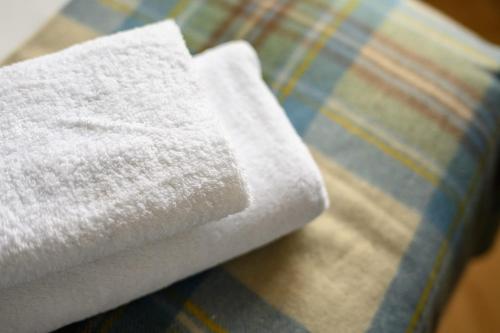 a pile of white towels sitting on a bed at Queen Charlotte Guesthouse in Edinburgh