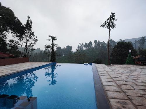 a swimming pool with blue water and trees in the background at Green Garden Holiday Home Wayanad in Vythiri