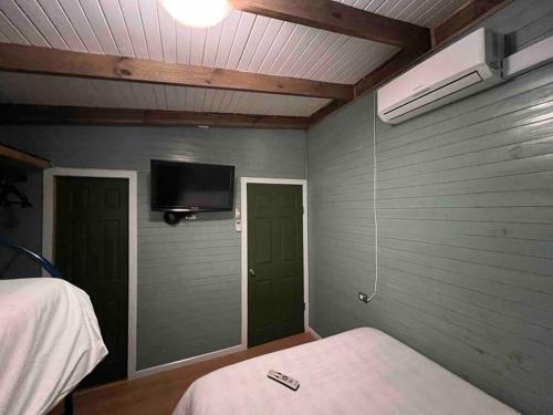 1 dormitorio con 1 cama y TV en la pared en Espectacular Tiny House,terraza,Aire acondicionado en Puerto Octay