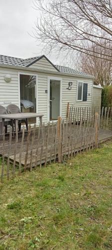 a house with a wooden fence and a picnic table at Luxueuze stacaravan 4pers met terras en tuintje Bredene (2010) in Bredene