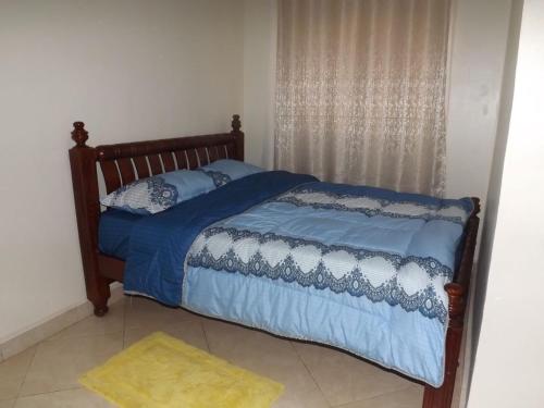 a bed with blue comforter and pillows in a bedroom at Malaika Furnished Apartments in Kampala