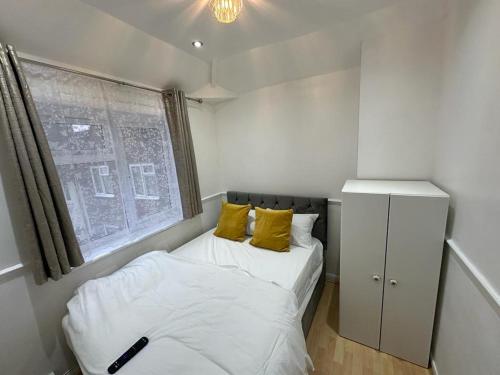 um pequeno quarto com 2 camas e uma janela em Cosy Smart/Small Double Room in Keedonwood Road Bromley em Bromley