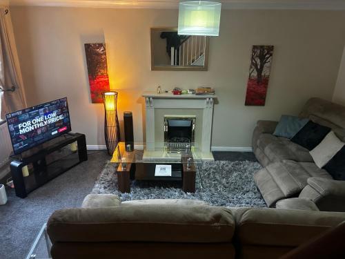 a living room with a couch and a fireplace at Brades Rise House - 3 bedroom house with 2 toilets with a private garden in Birmingham