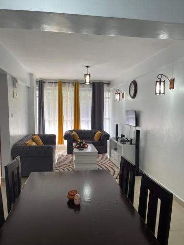 uma sala de estar com uma mesa e um sofá em Zoe Homes Oak Villa Apartment 1 and 2 Bedroom 201 em Kericho