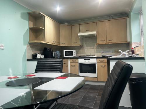a kitchen with wooden cabinets and a table with chairs at Brades Rise House - 3 bedroom house with 2 toilets with a private garden in Birmingham
