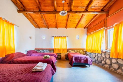 a room with three beds and a stone wall at Aguada Escondida in San Marcos Sierras