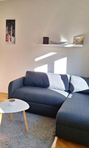 a living room with a blue couch and a table at Léna's apartman in Pécs