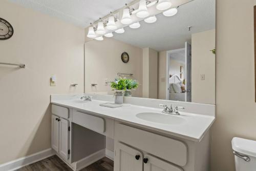 a bathroom with a sink and a large mirror at Oceans At The Grove By Hostique in Myrtle Beach