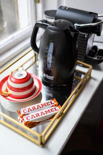 a counter top with a coffee pot and a packet of candy at Queen Charlotte Guesthouse in Edinburgh
