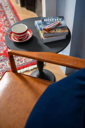 a table with a cup and a book and a cup and saucer at Queen Charlotte Guesthouse in Edinburgh