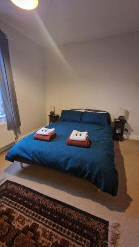 a bedroom with a blue bed with two towels on it at Stamford - 2 bed terrace house in Lincolnshire