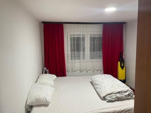 een slaapkamer met een bed met rode gordijnen en een gitaar bij Apartman Delfin in Grahovište