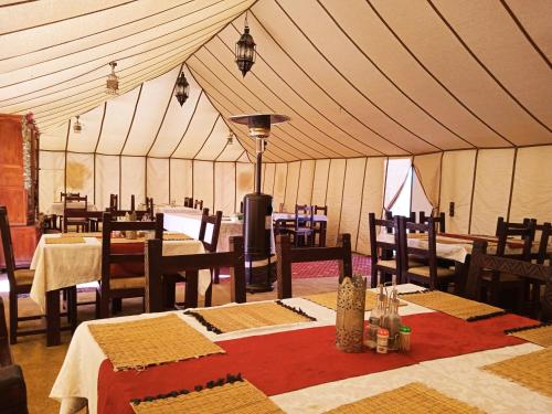 a tent with tables and chairs in a room at Sahara Luxury Camp in Merzouga