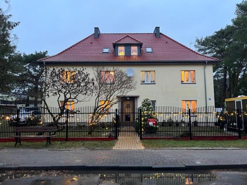 a large white house with a black fence at Stay Adventure Mrzeżyno in Mrzeżyno