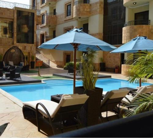 فندق اي دبليو جي  أبحر  في جدة: مسبح وكراسي ومظلات بجانب مبنى